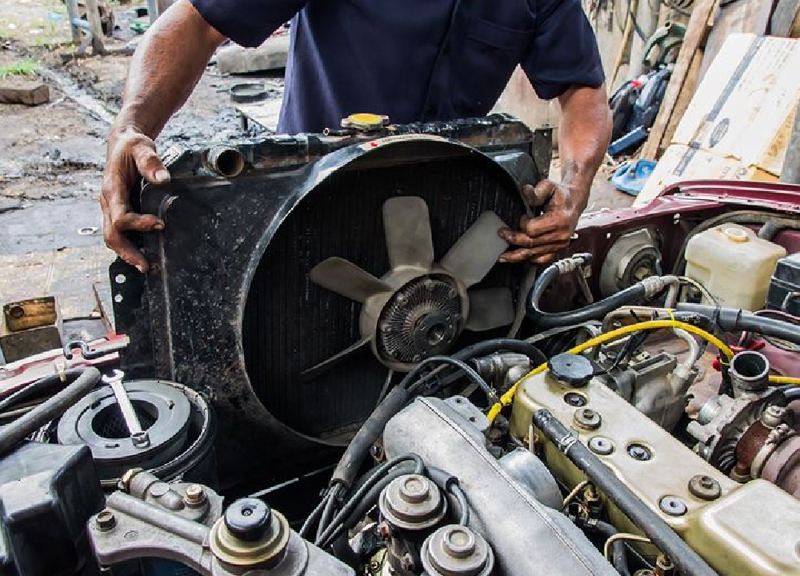 Mechanic repairing a car radiator and cooling fan